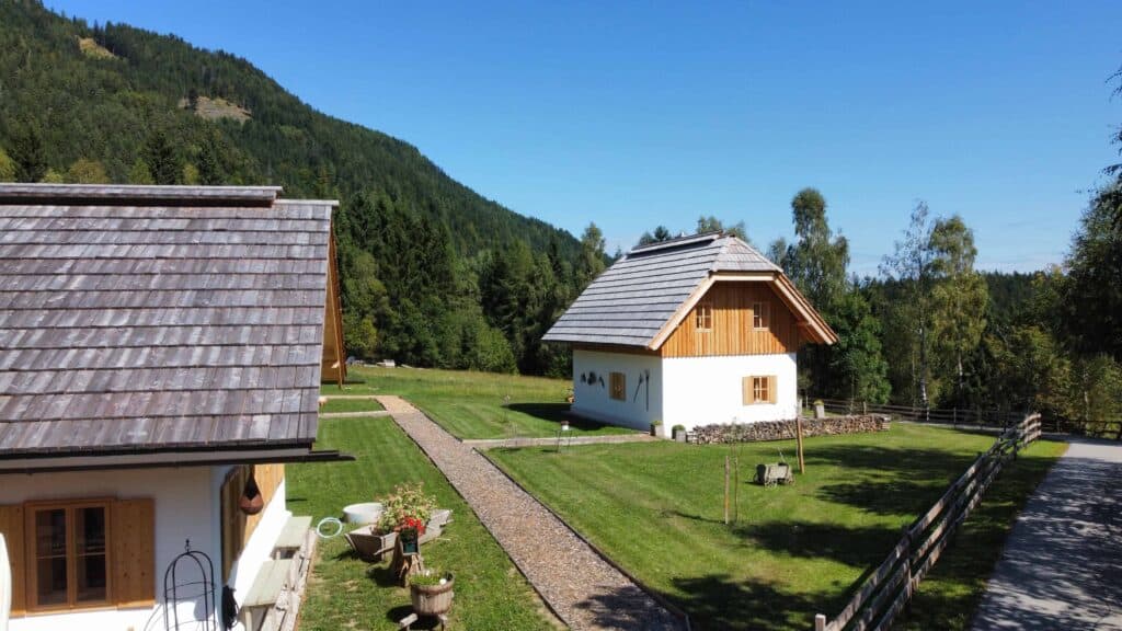 Chalets im Grünen, umgeben von Wäldern und Bergen, Bauernhäuser im traditionellen alpinen Stil.