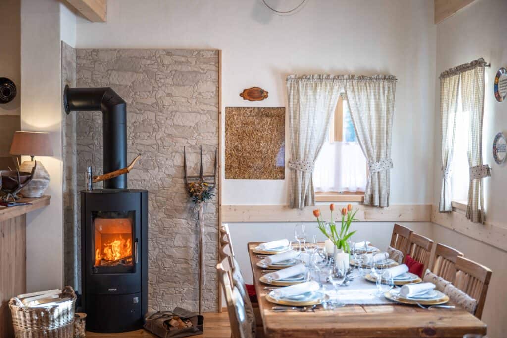 Dorfschenke beim Ebner 1822 - Accogliente sala da pranzo con camino, arredi rustici e tavola ben apparecchiata per i pasti in famiglia.
