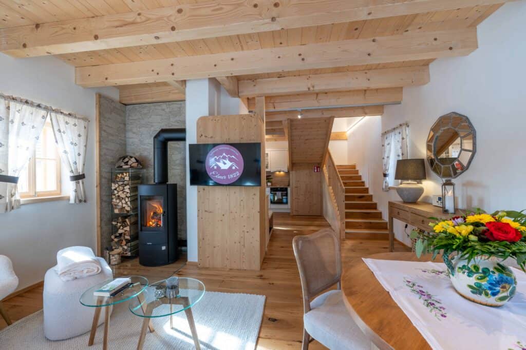 Ebner 1822 Gemütliches Wohnzimmer mit Holzdecke, Kamin und moderner Einrichtung bei Ebner1822.