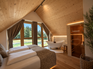 Ruhiger Schlafbereich im Naturhaus von Ebner 1822 in Kärnten mit Holz, Badewanne, Sauna und Blick ins Grüne