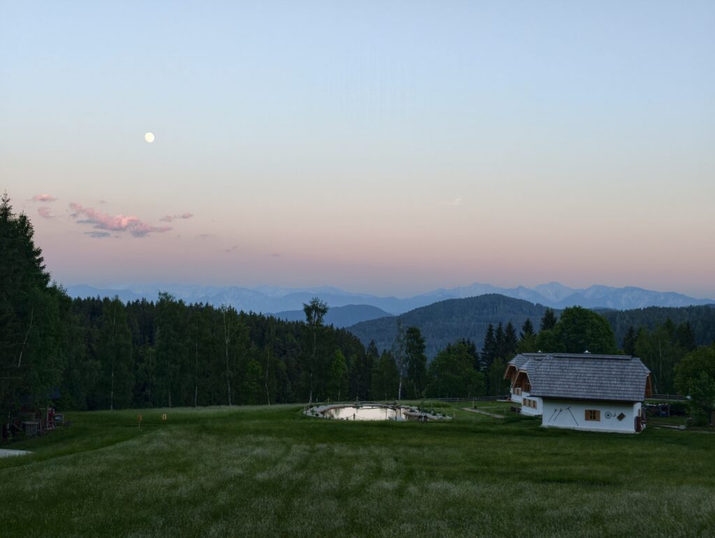 Naturhaus von Ebner 1822 in Kärnten mit Naturteich, Wiesen und Blick auf die Berge in ruhiger Abendstimmung