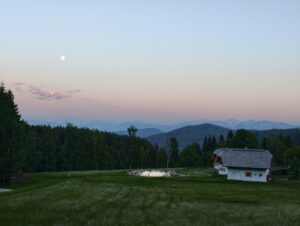 Naturhaus von Ebner 1822 in Kärnten mit Naturteich, Wiesen und Blick auf die Berge in ruhiger Abendstimmung