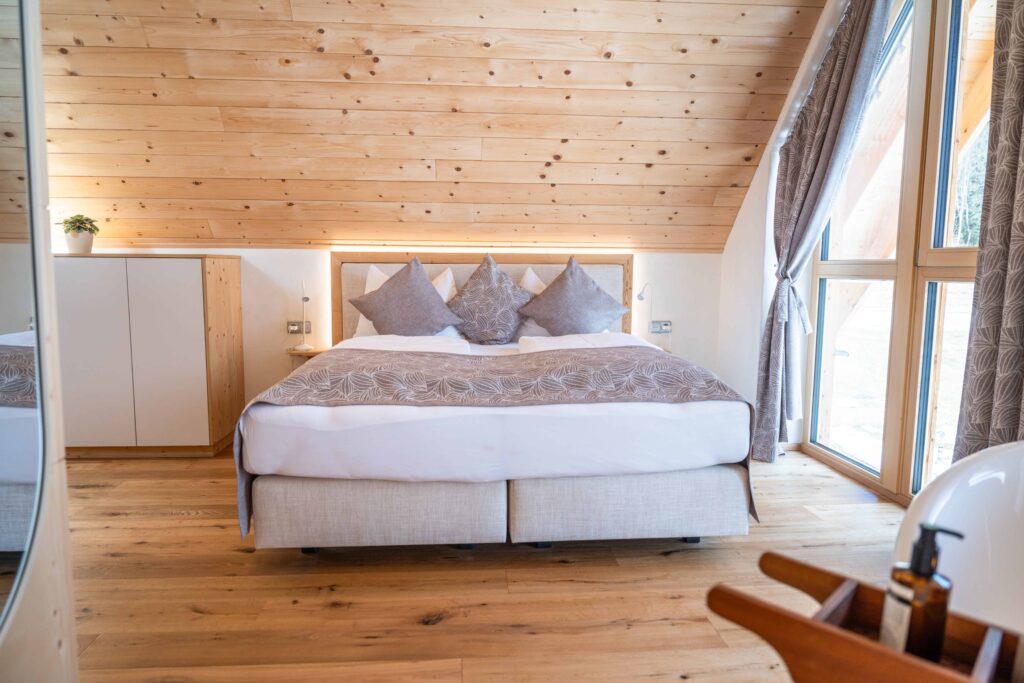 Helles Schlafzimmer im Naturhaus bei Ebner 1822 mit Lehmwänden, Holzdecke, Doppelbett und großen Fenstern
