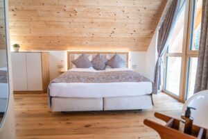 Helles Schlafzimmer im Naturhaus bei Ebner 1822 mit Lehmwänden, Holzdecke, Doppelbett und großen Fenstern